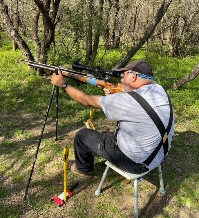 A person sitting on a chair aiming a rifle  AI-generated content may be incorrect.