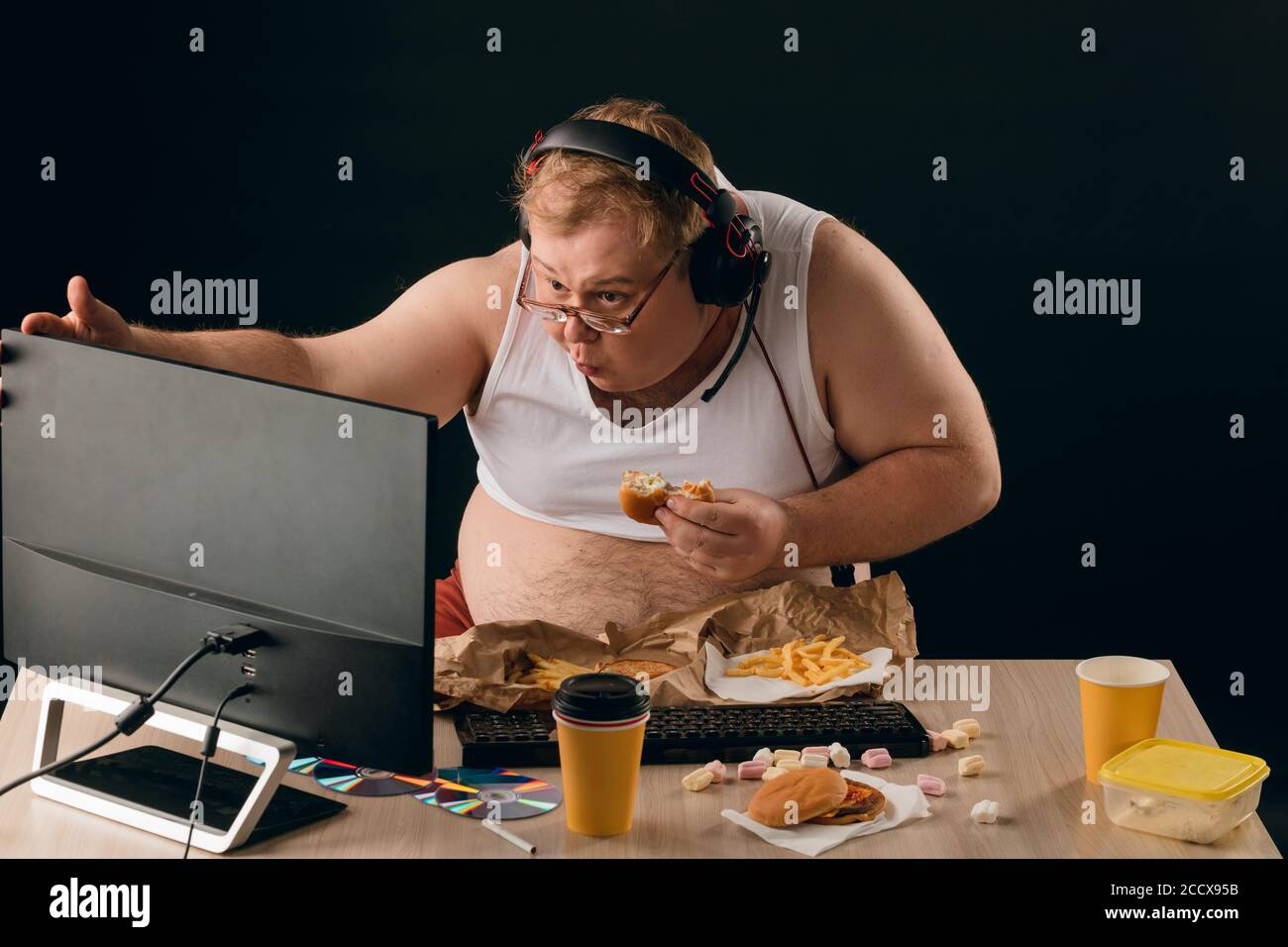 funny-plump-man-staring-at-the-screen-of-the-computer-and-eating-a-hamburger-close-up-photostu...jpg
